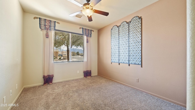 empty room with carpet floors, ceiling fan, visible vents, and baseboards