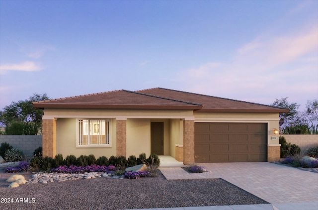 view of front facade with decorative driveway, fence, an attached garage, and stucco siding