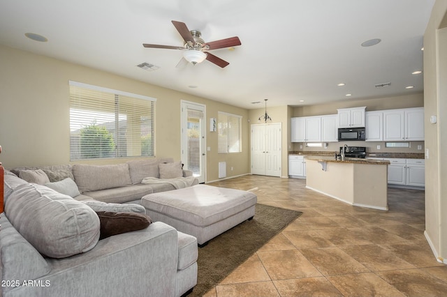 living room with sink, light tile patterned floors, and ceiling fan