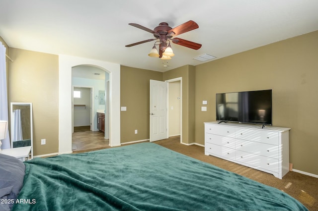 bedroom featuring ceiling fan, ensuite bath, and dark colored carpet