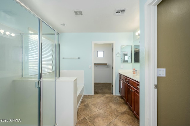 bathroom featuring vanity, plus walk in shower, tile patterned flooring, and a wealth of natural light