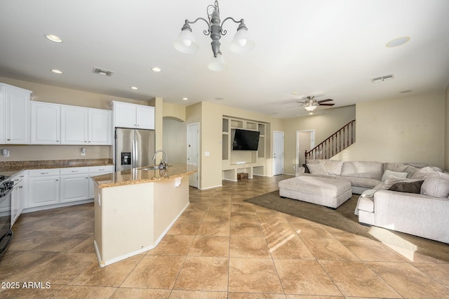 kitchen featuring white cabinetry, sink, a kitchen island with sink, light stone counters, and stainless steel refrigerator with ice dispenser