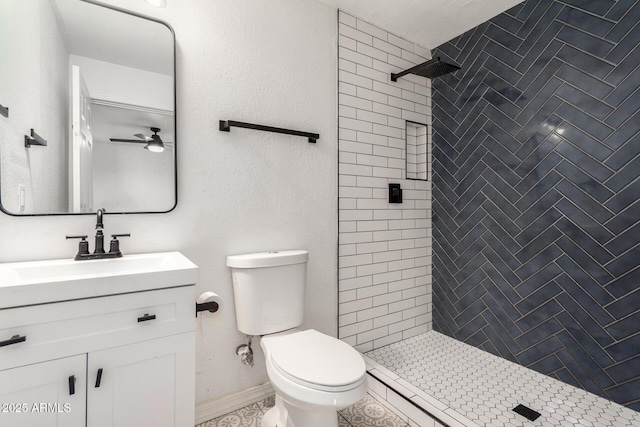 bathroom featuring ceiling fan, vanity, toilet, and a tile shower