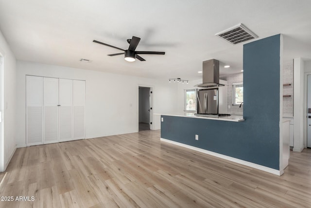 unfurnished living room with ceiling fan and light wood-type flooring