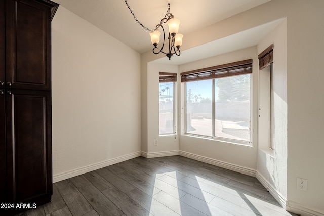 unfurnished dining area with hardwood / wood-style floors and a chandelier