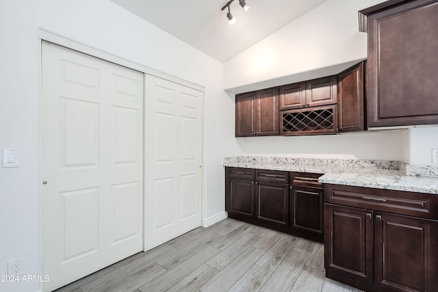 kitchen featuring dark brown cabinetry, light hardwood / wood-style floors, and lofted ceiling