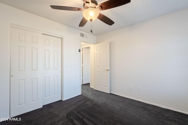 unfurnished bedroom featuring ceiling fan, a closet, and dark carpet