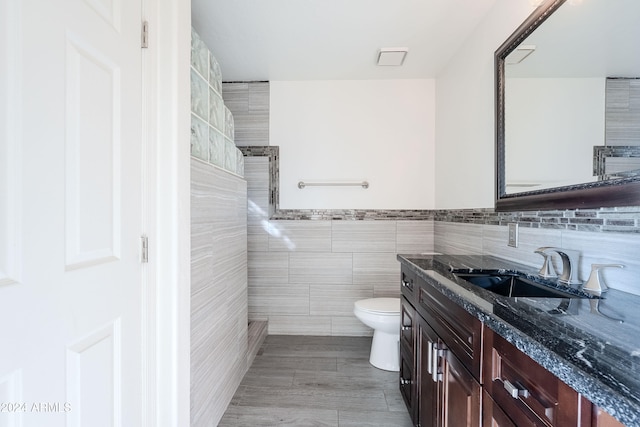 bathroom featuring vanity, toilet, and tile walls