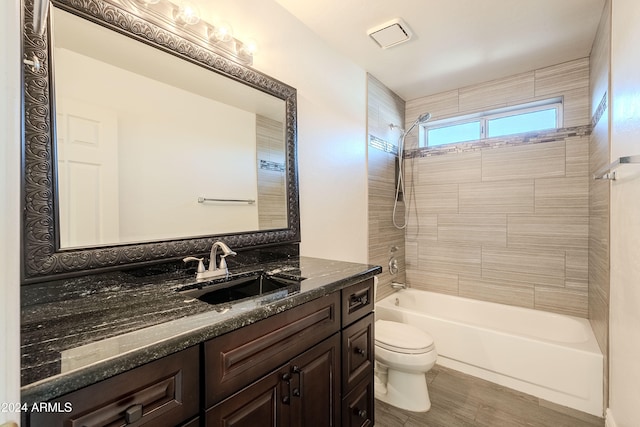 full bathroom with vanity, wood-type flooring, tiled shower / bath, and toilet