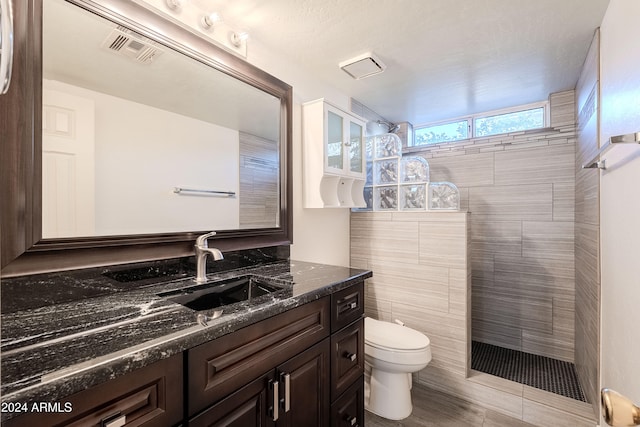 bathroom featuring vanity, toilet, and a tile shower