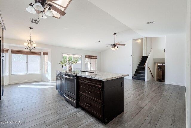 kitchen featuring stainless steel electric range, decorative light fixtures, dark brown cabinetry, an island with sink, and light hardwood / wood-style flooring