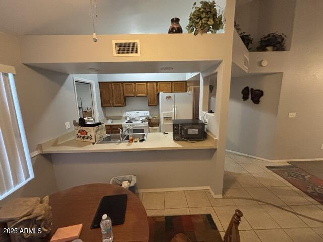 kitchen with sink, light tile patterned floors, white appliances, and kitchen peninsula