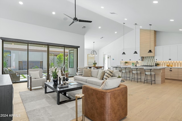 living room featuring light hardwood / wood-style floors, high vaulted ceiling, ceiling fan, and sink