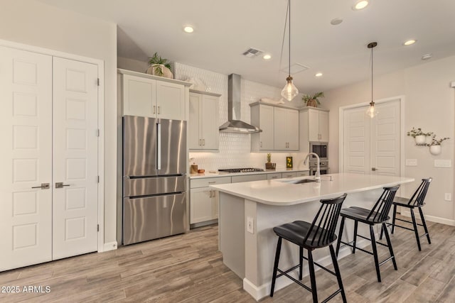 10447 W Salter Dr, Peoria, AZ 85382 - kitchen with appliances with stainless steel finishes, a sink, wall chimney range hood, light wood-type flooring, and recessed lighting