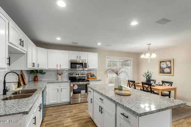 kitchen featuring appliances with stainless steel finishes, backsplash, a sink, and wood finish floors