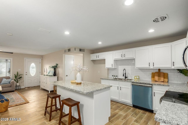 kitchen featuring dishwasher, light wood finished floors, a sink, and visible vents