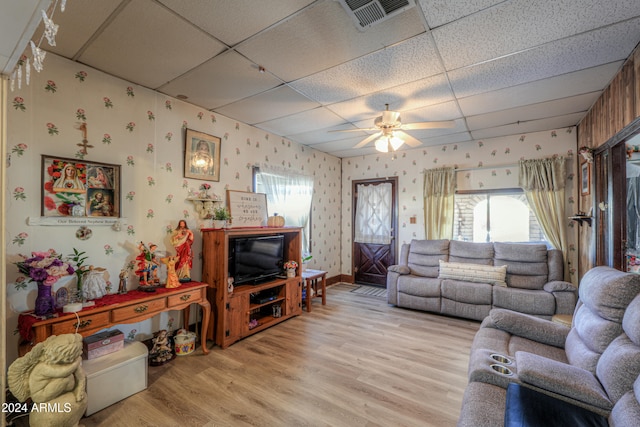 living room with light hardwood / wood-style flooring, a drop ceiling, and ceiling fan