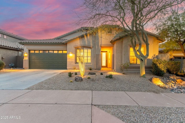 view of front of house with a garage, concrete driveway, and stucco siding