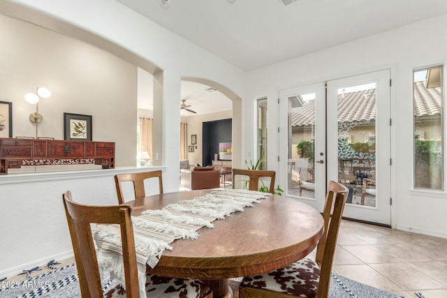 dining area with a ceiling fan, arched walkways, plenty of natural light, and light tile patterned floors