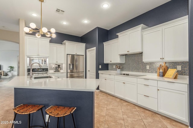 kitchen featuring visible vents, white cabinets, stainless steel appliances, light countertops, and a sink