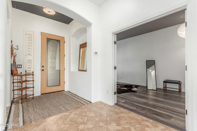 tiled entrance foyer with arched walkways and baseboards