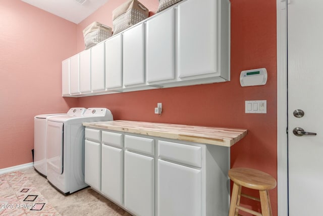 washroom featuring cabinet space, washing machine and dryer, and baseboards