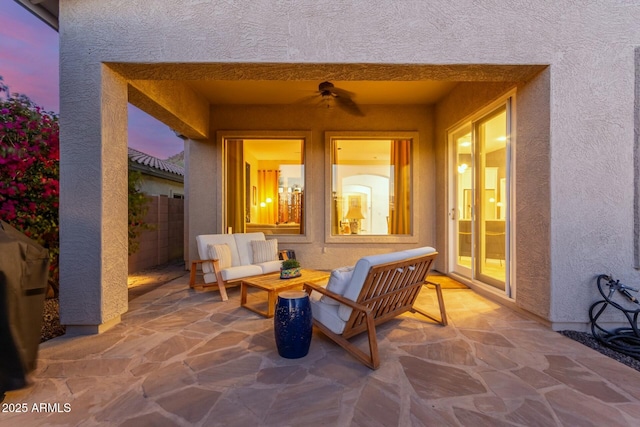 patio terrace at dusk with a ceiling fan, outdoor lounge area, and fence