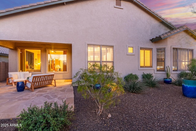 back of property at dusk featuring a patio, fence, a tiled roof, and stucco siding