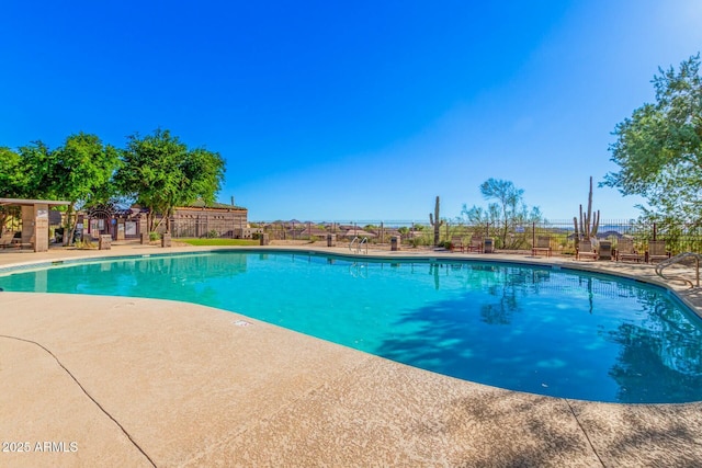 community pool with a patio area and fence