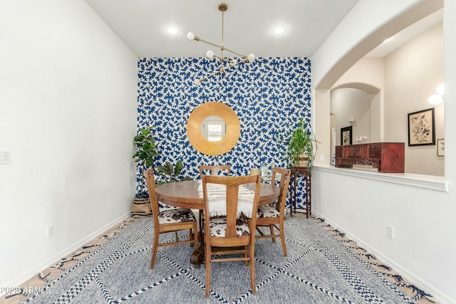 dining space with an accent wall, baseboards, arched walkways, and recessed lighting