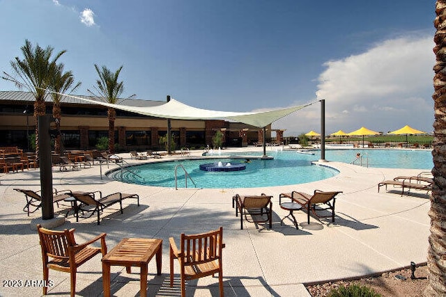 view of swimming pool with pool water feature and a patio area