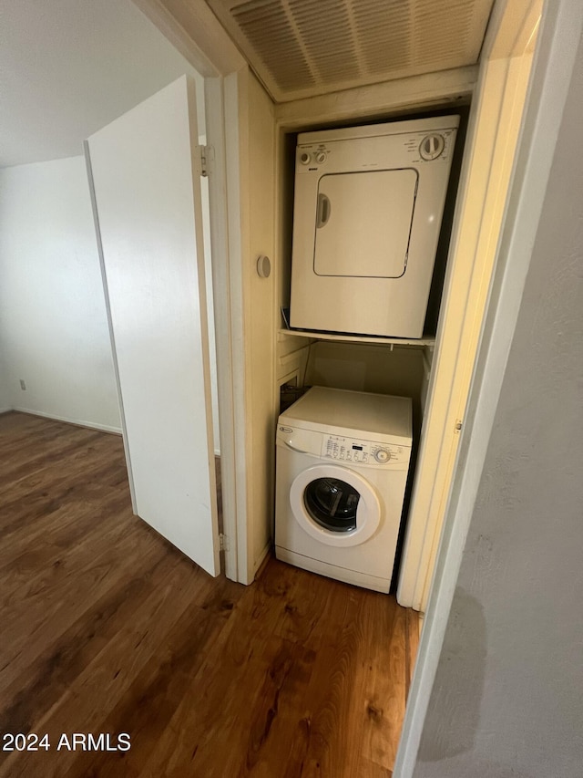 laundry room featuring stacked washer and dryer, laundry area, and wood finished floors