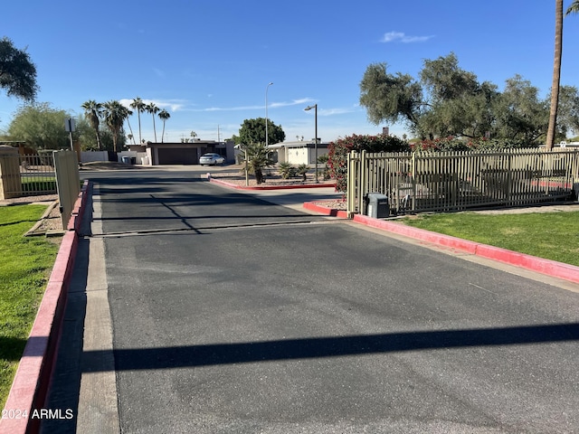 view of road featuring street lights, curbs, and a gated entry