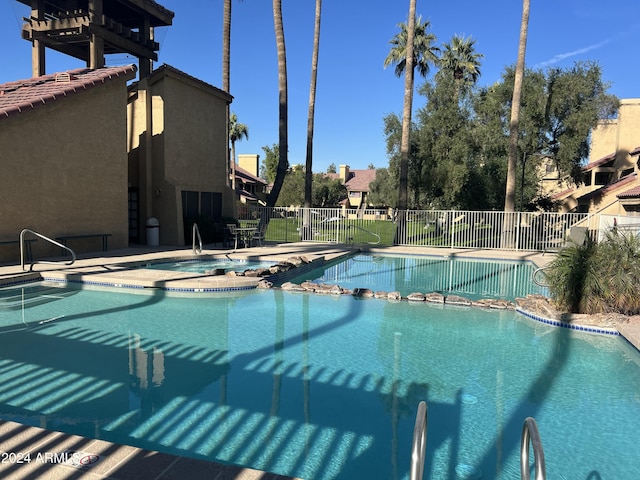 pool featuring a patio area, fence, and a hot tub