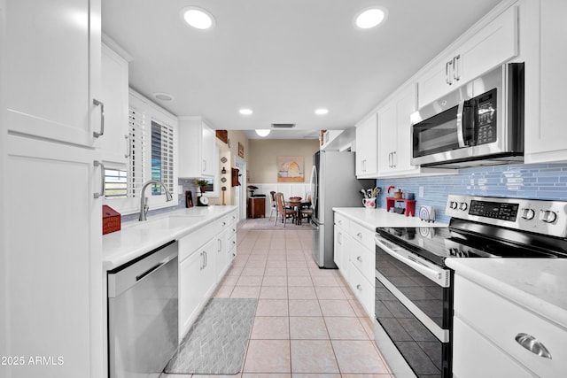 kitchen featuring stainless steel appliances, white cabinetry, sink, and backsplash