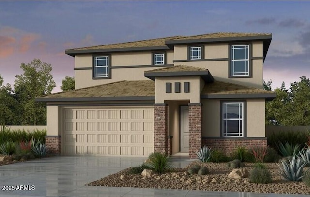 prairie-style house featuring concrete driveway, brick siding, an attached garage, and stucco siding