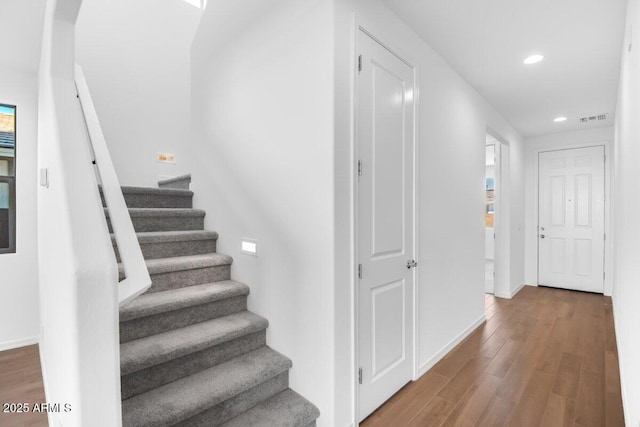 stairway with baseboards, visible vents, wood finished floors, and recessed lighting