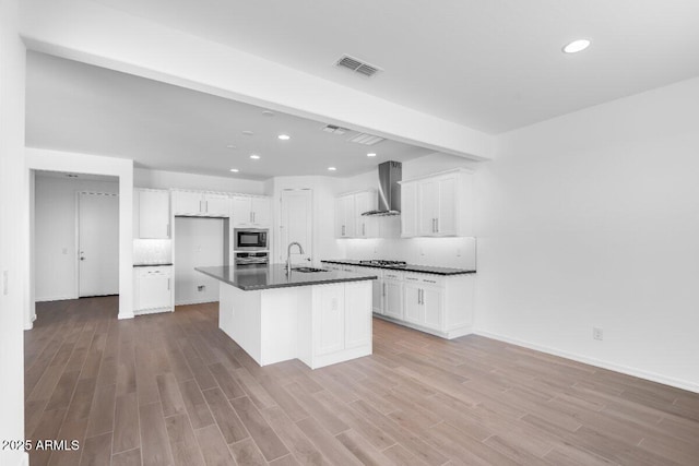 kitchen with cooktop, visible vents, dark countertops, wall chimney exhaust hood, and built in microwave