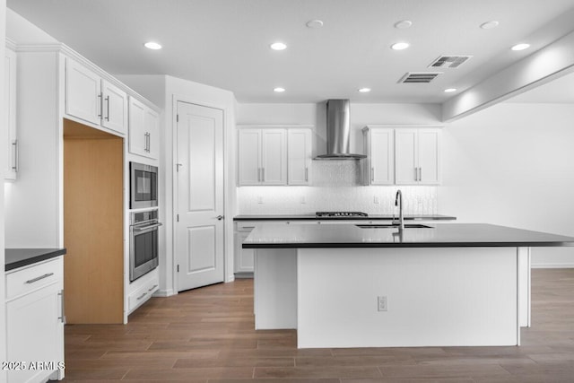 kitchen with visible vents, a sink, stainless steel oven, built in microwave, and wall chimney exhaust hood