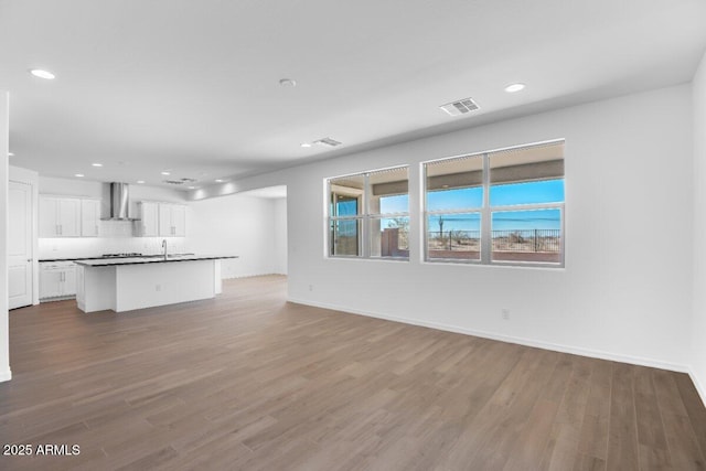 unfurnished living room featuring baseboards, visible vents, wood finished floors, and recessed lighting