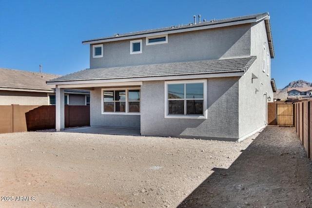 rear view of house featuring a tile roof, a fenced backyard, and stucco siding