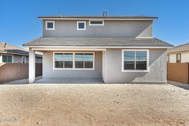 rear view of property with fence private yard, a tiled roof, and stucco siding