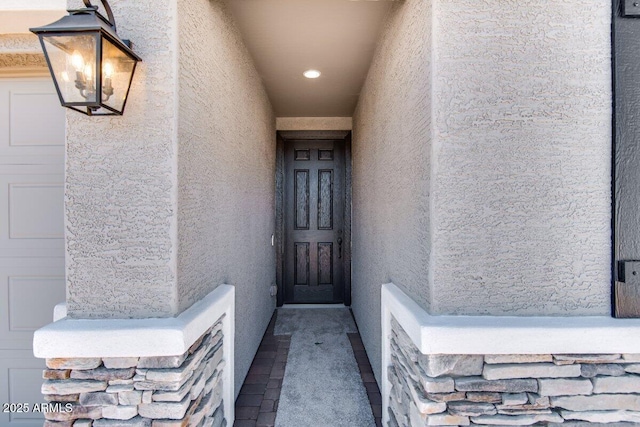 doorway to property with an attached garage and stucco siding