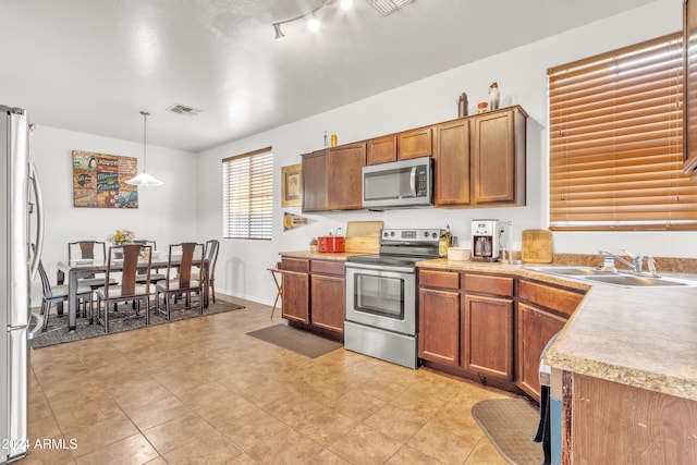 kitchen featuring sink, rail lighting, decorative light fixtures, and appliances with stainless steel finishes