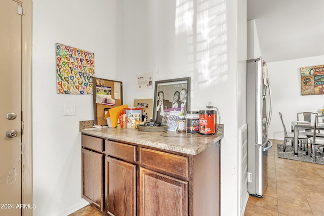 bar featuring stainless steel fridge and light tile patterned floors