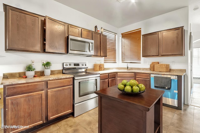 kitchen with a center island, light tile patterned flooring, stainless steel appliances, and a wealth of natural light