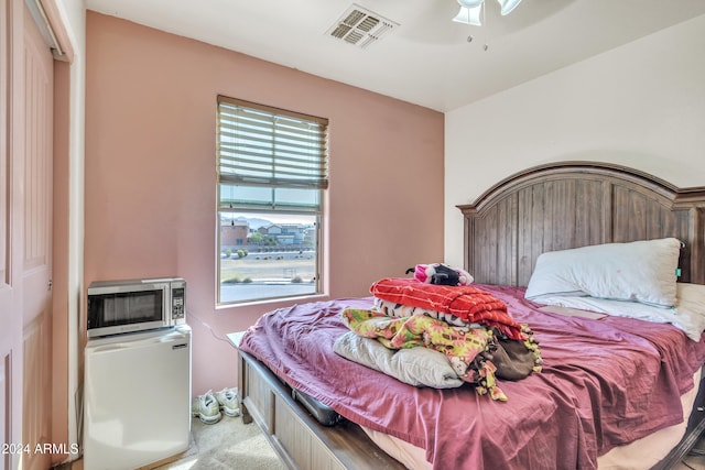 bedroom featuring ceiling fan, light carpet, and fridge