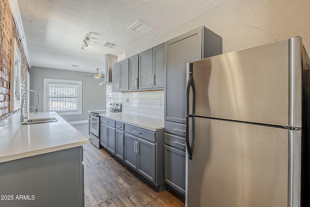kitchen with appliances with stainless steel finishes, a sink, gray cabinetry, and dark wood finished floors