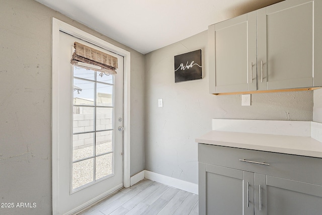 doorway featuring baseboards and light wood finished floors