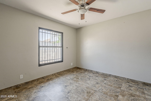empty room with stone finish floors and a ceiling fan